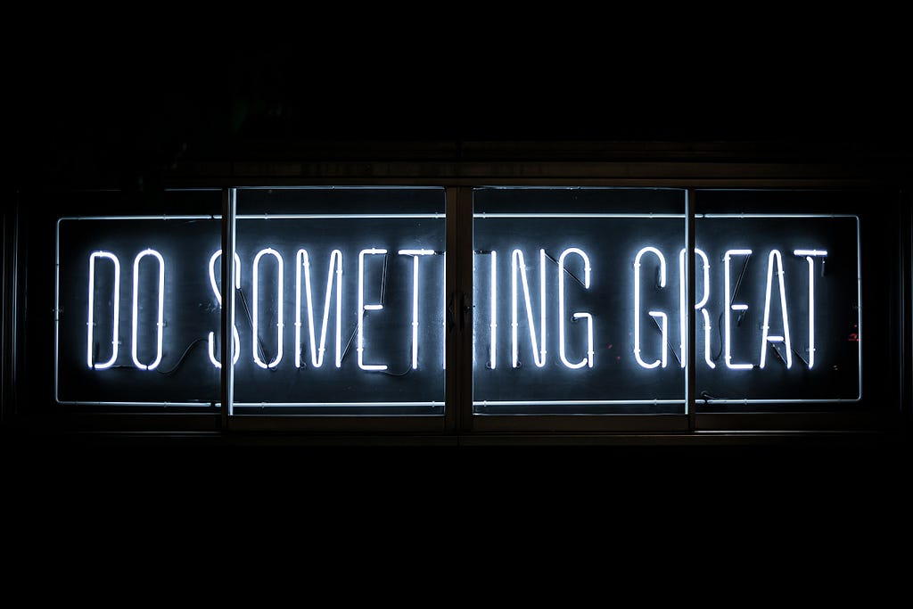 A photograph of a neon sign that says “Do something great.”