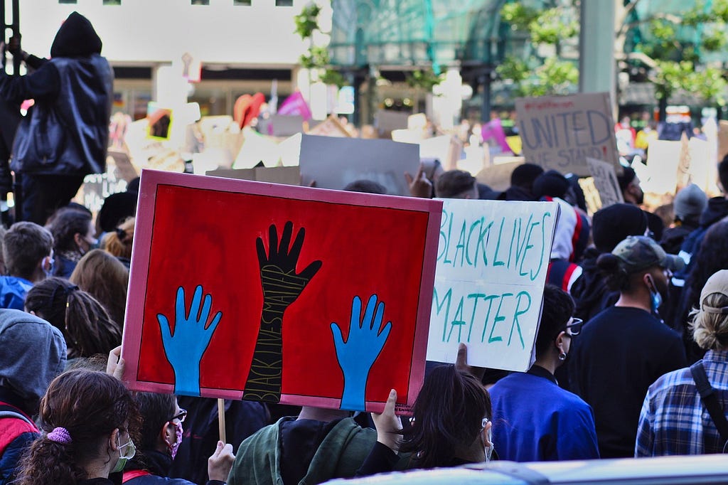 Registro de una multitud en protesta del movimiento ‘Black Lives Matter’: todos de espaldas y muchos exhibiendo carteles sobre el tema.