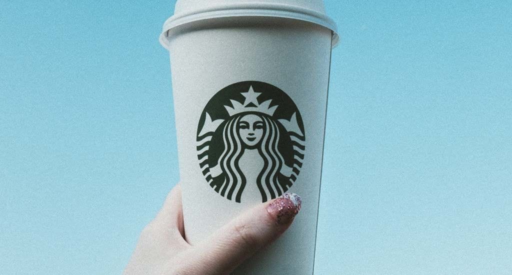 Woman holding Luckin coffee competitor Starbucks coffee cup