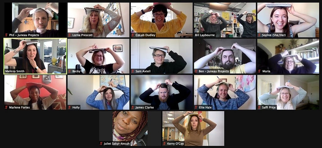 Screenshot of 17 screens from the zoom where each session participant has their paper on their head to draw their face