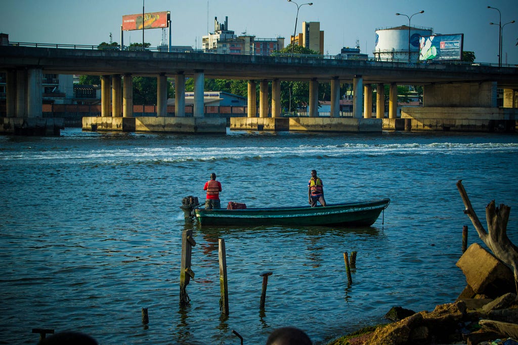 fishermen working under a bridge in Lagos on their canoes on the ocean