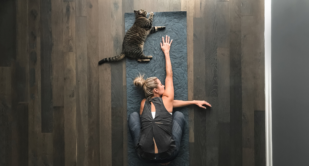 Woman and her cat do yoga together.