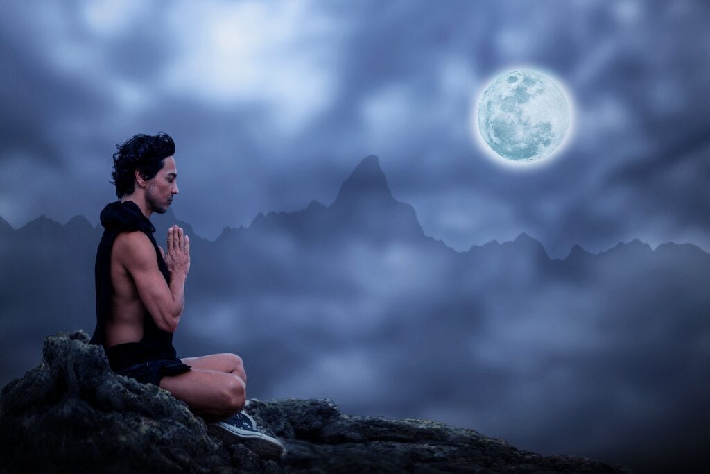 Man meditating facing the full moon