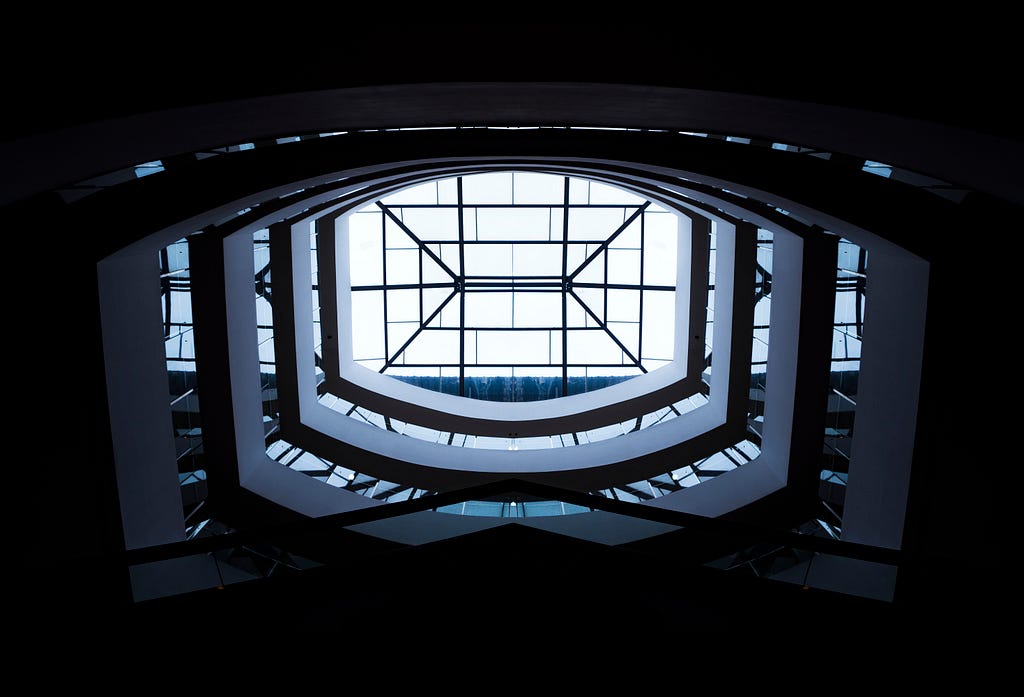 Low-angle photography of white building interior with clear glass roof during daytime this represents brand architecture.