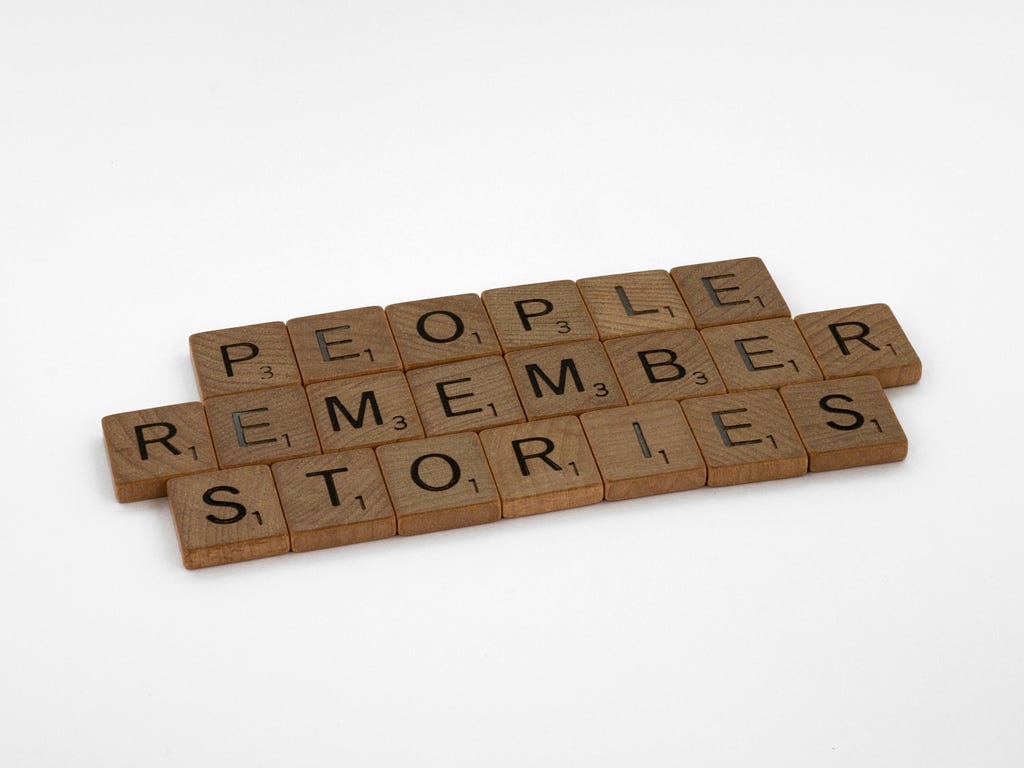 Image of scrabble pieces in three lines on a white background, spelling out “people remember stories.”