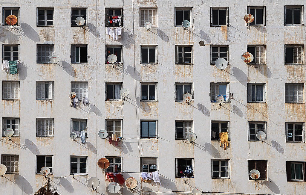 An apartment complex with antennas hanging out of the windows.