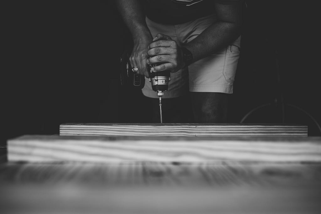 A person drilling a hole in a piece of wood