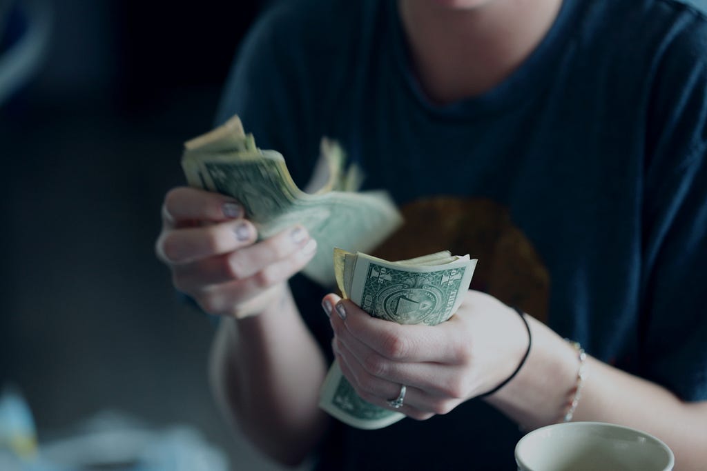 A white male counting dollars as savings are needed for a Digital Nomad to start his trip