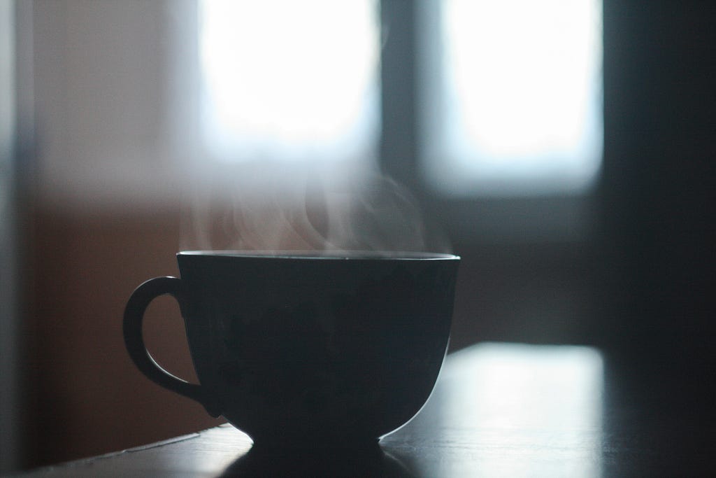 A steaming mug of tea on a table.