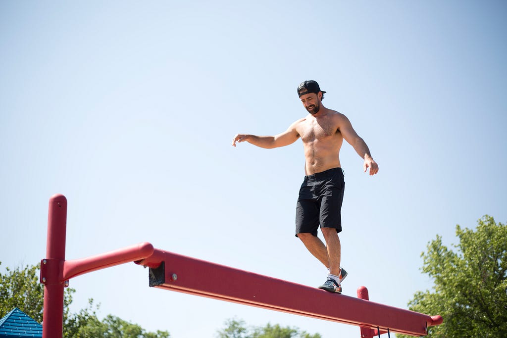 a man walking on a beam across a river.