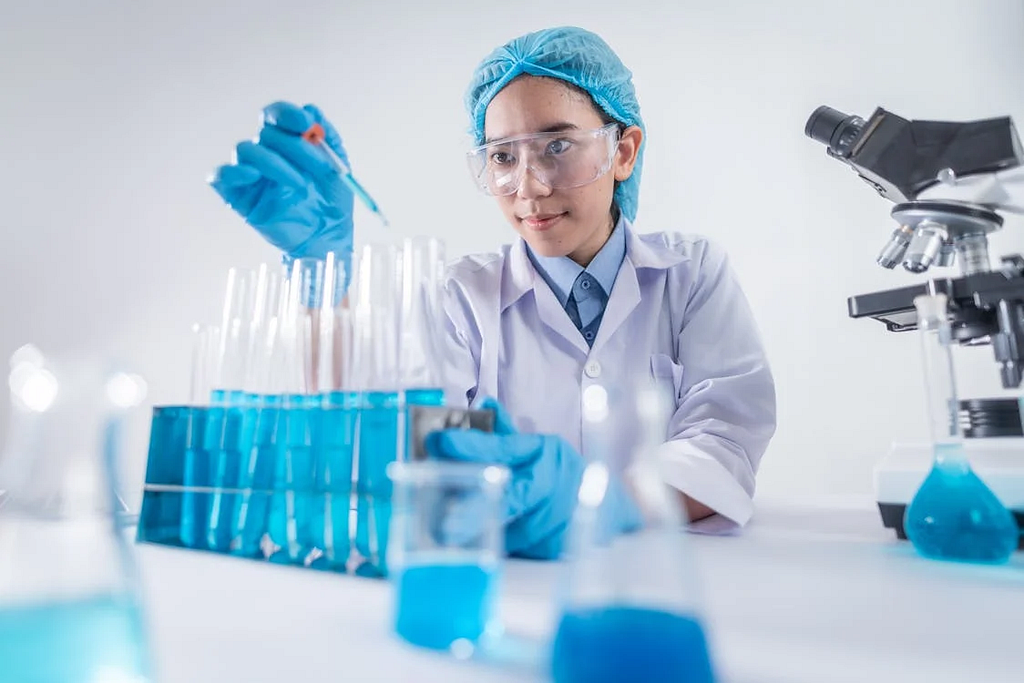 A photo of a female scientist wearing a lab coat and gloves carefully using a pipette in a laboratory.