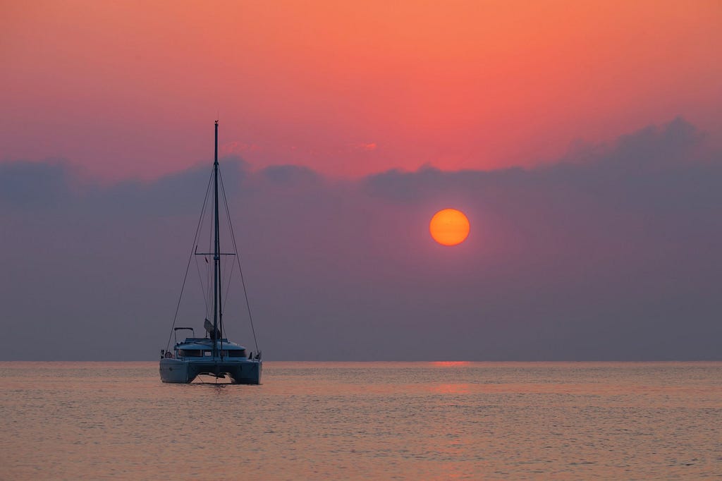 A sailboat in the water at sunset.