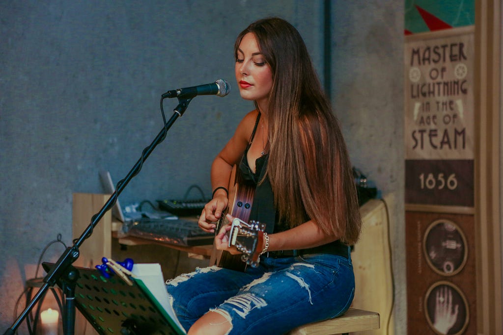 A woman singing though a guitar