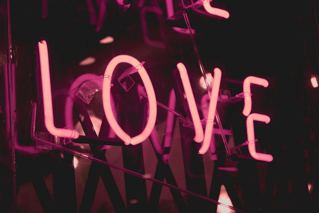 Pink neon lights create the word “love”.