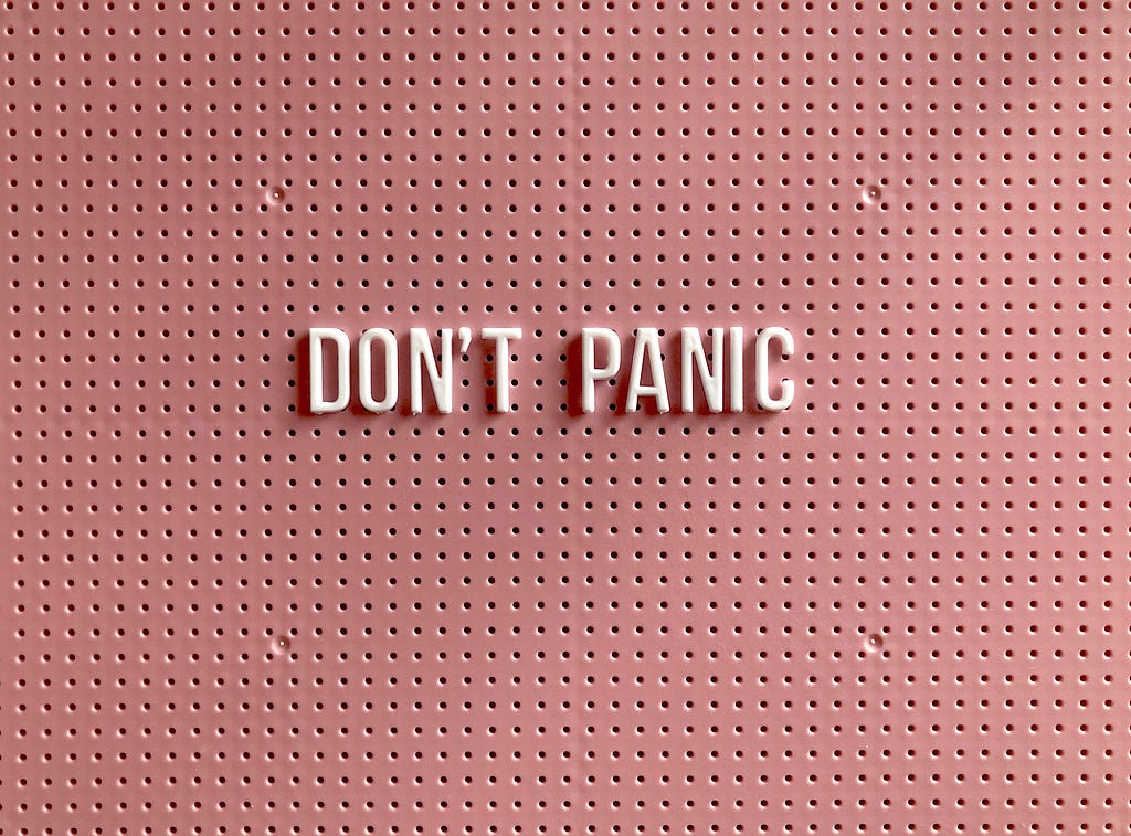 Pink sign saying “Don’t Panic”