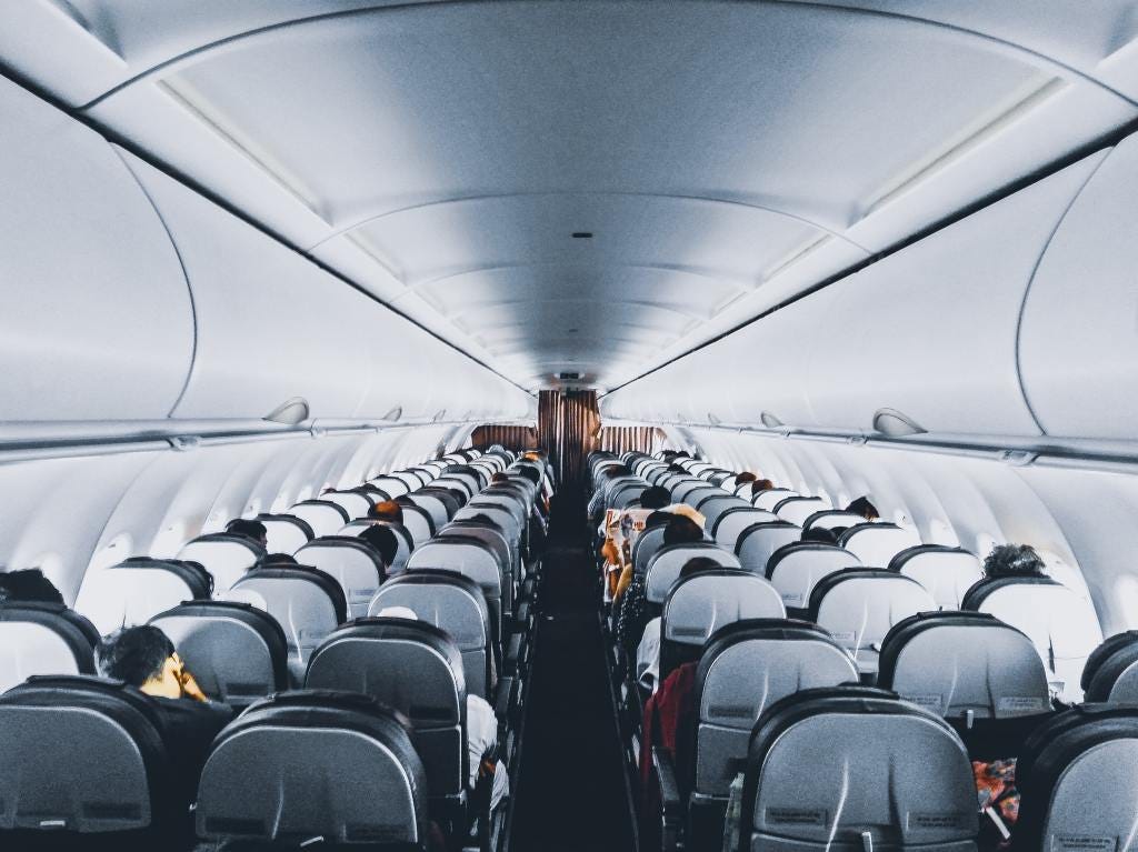 Airplane seat rows are displayed from the back of the airplane