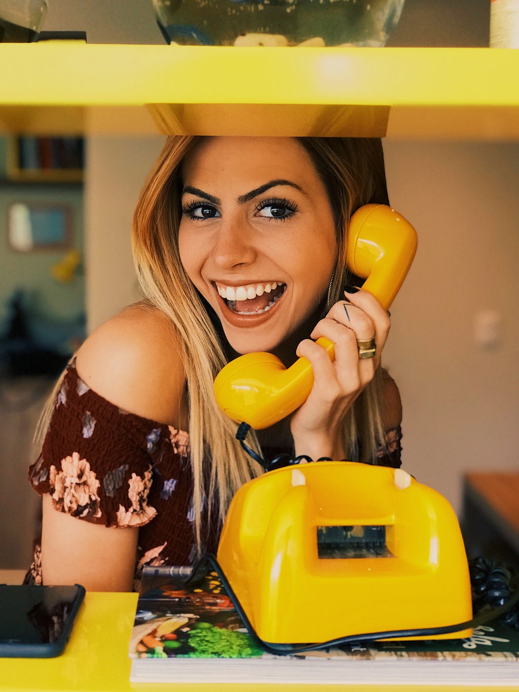 A person on the telephone, holding the receiver to their ear and looking exaggeratedly happy
