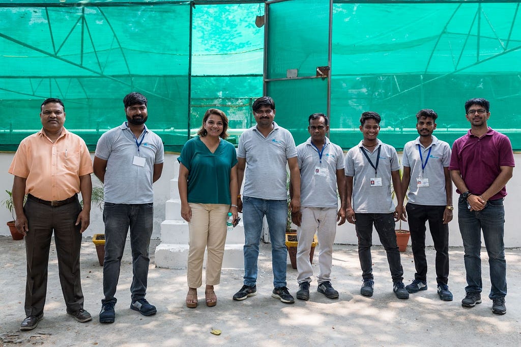 Group of eight individuals — one female and seven males in front of a wastewater treatment system.