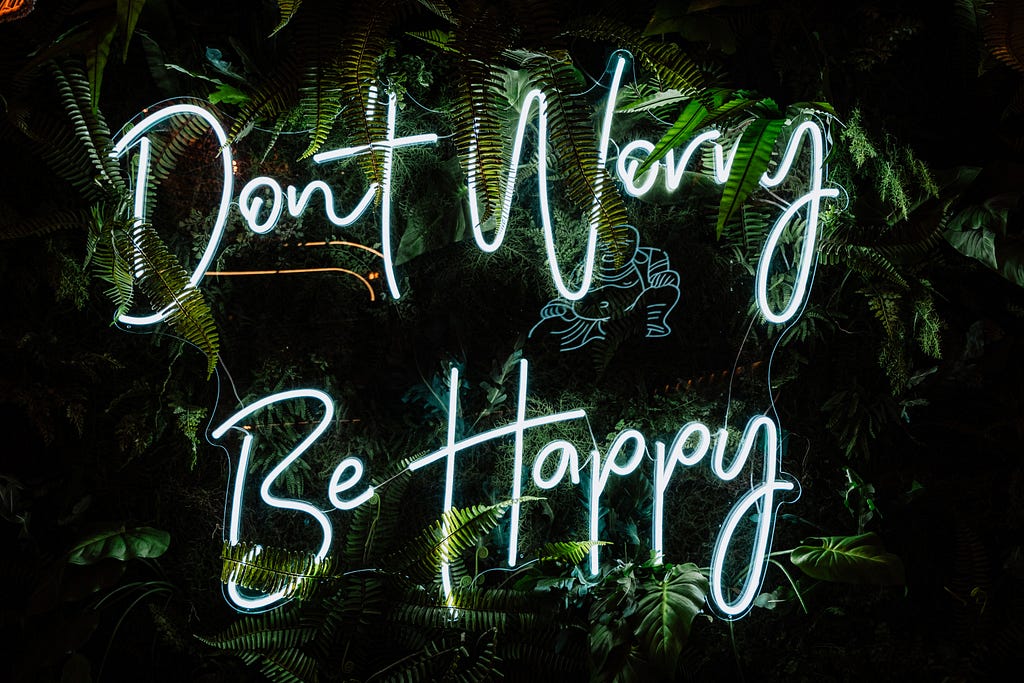 Photo of “Don’t Worry Be Happy” in white neon.