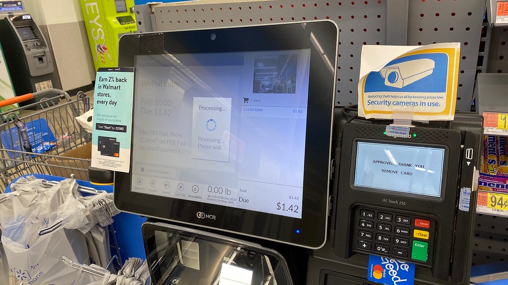 Self checkout machine from Walmart that instructs the user to wait while the payment is processing.