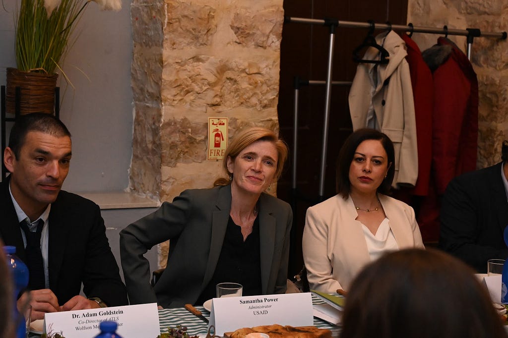 Women seated between a man and a woman intently listening during a seated table discussion.