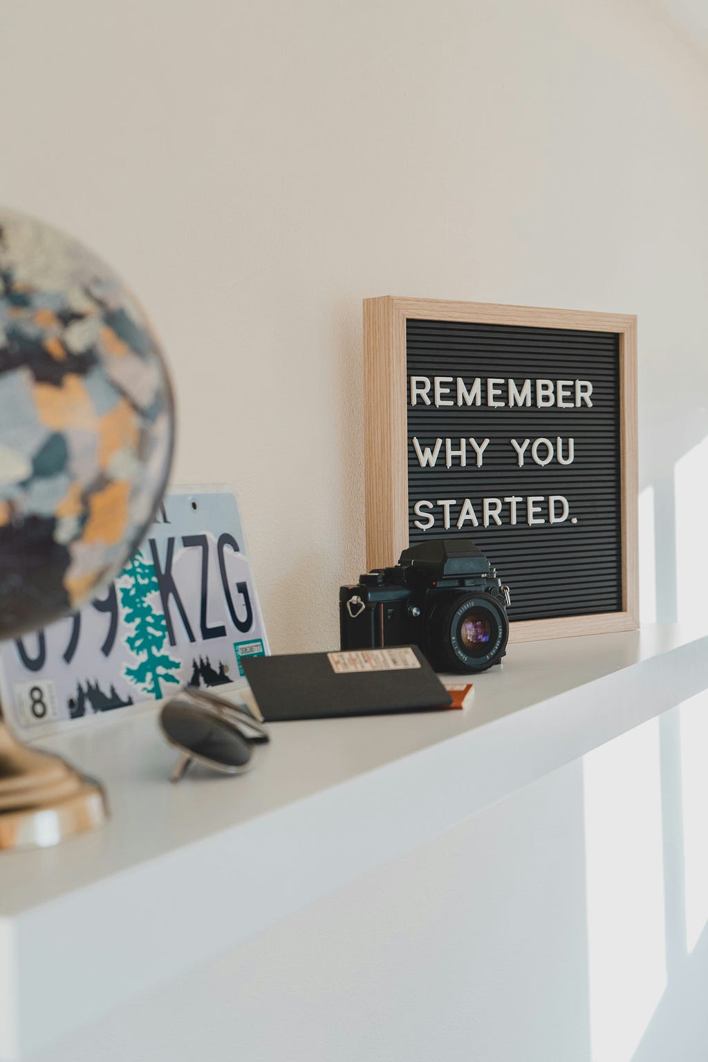 A picture frame sits on a shelf with the words inside the frame saying “Remember why you started”
