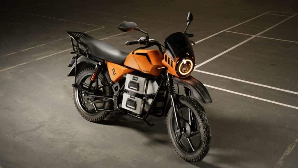 A moody photograph of a black and orange motorcycle against concrete