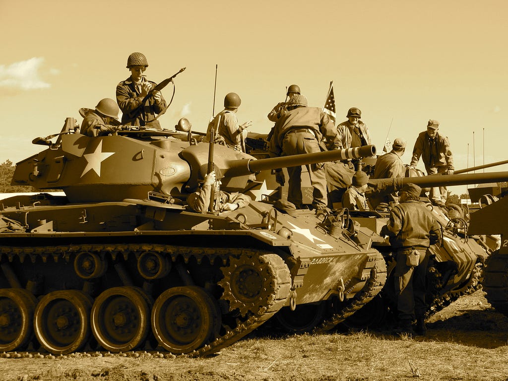 soilders standng on the tank with arms.