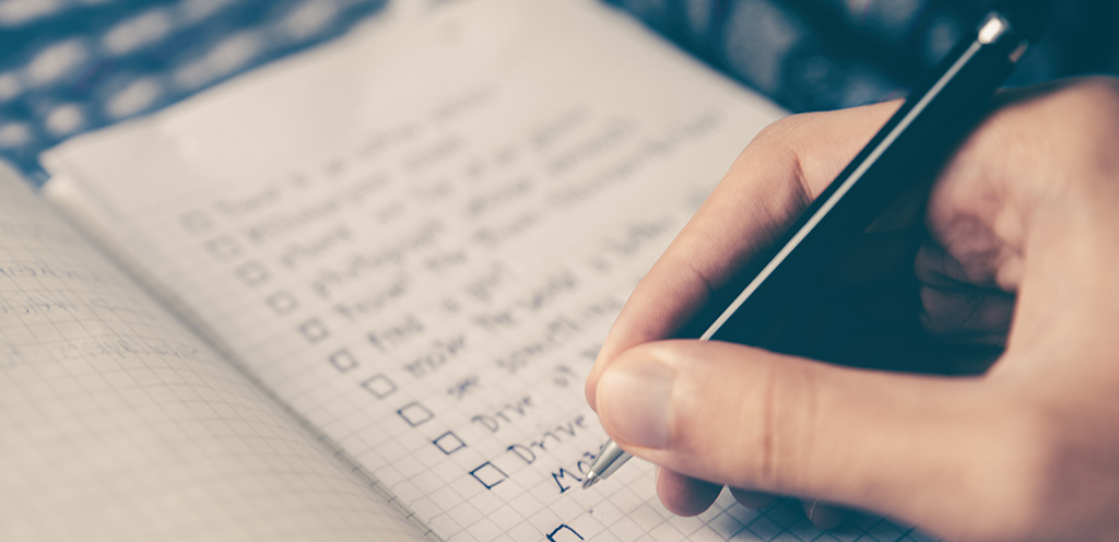 A hand writing goals into a journal.