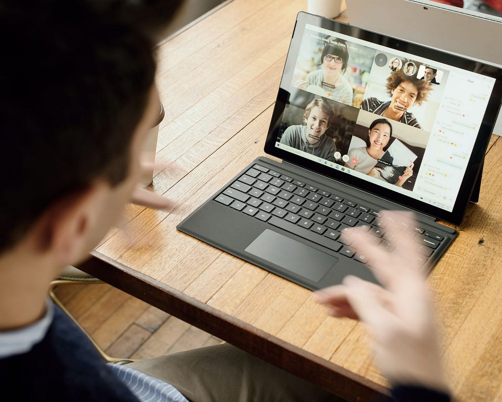 Point of view from a person looking into an open laptop showing a teleconference with four colleagues.