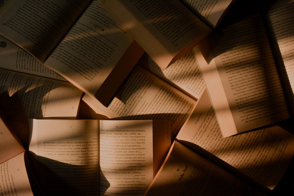 Books lying open on a surface with sepia colours and lots of shadows