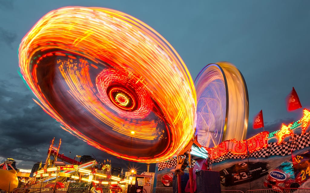 two Ferris wheels photographed with a slow shutter speed to produce a blur of lights