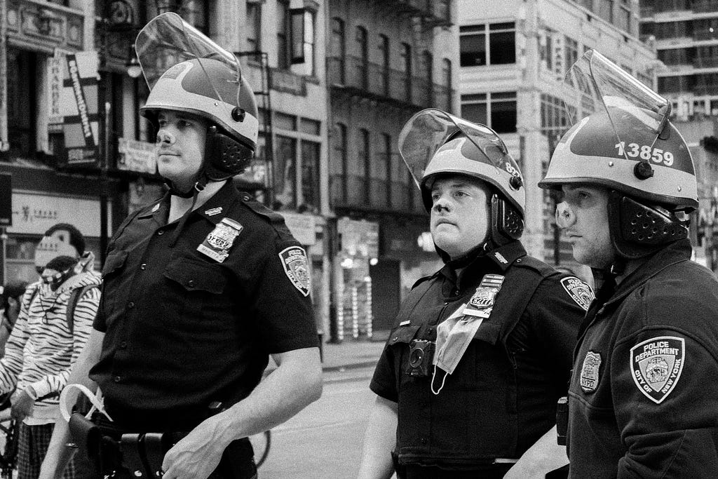 A trio of NYPD officers with pig snouts stand in the street