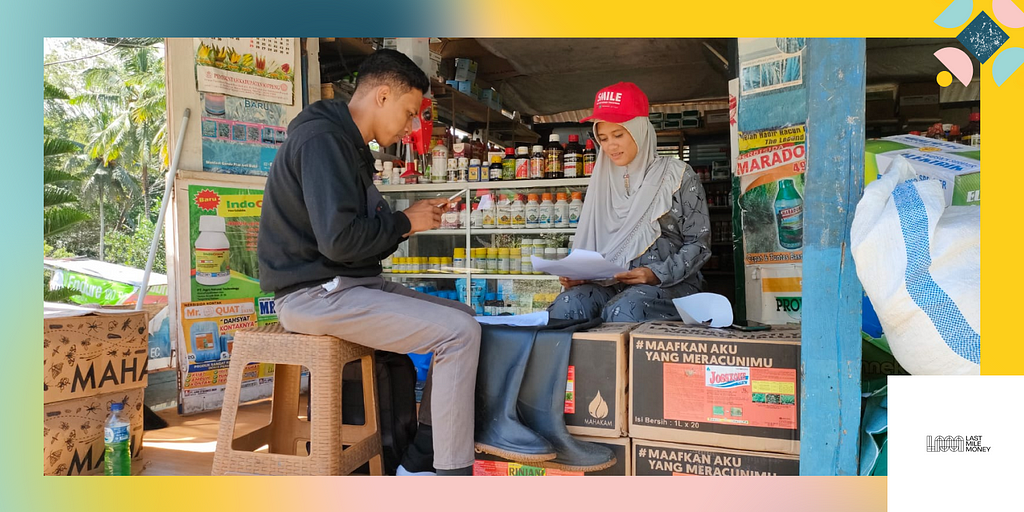 A photo of star agent Bo Arpina meets with a customer in her agri-kiosk. She wears a bright red hat with a grey headscarf and reviews a printed form. To the left, a male customer in a black hoodie reviews the transaction on his phone.