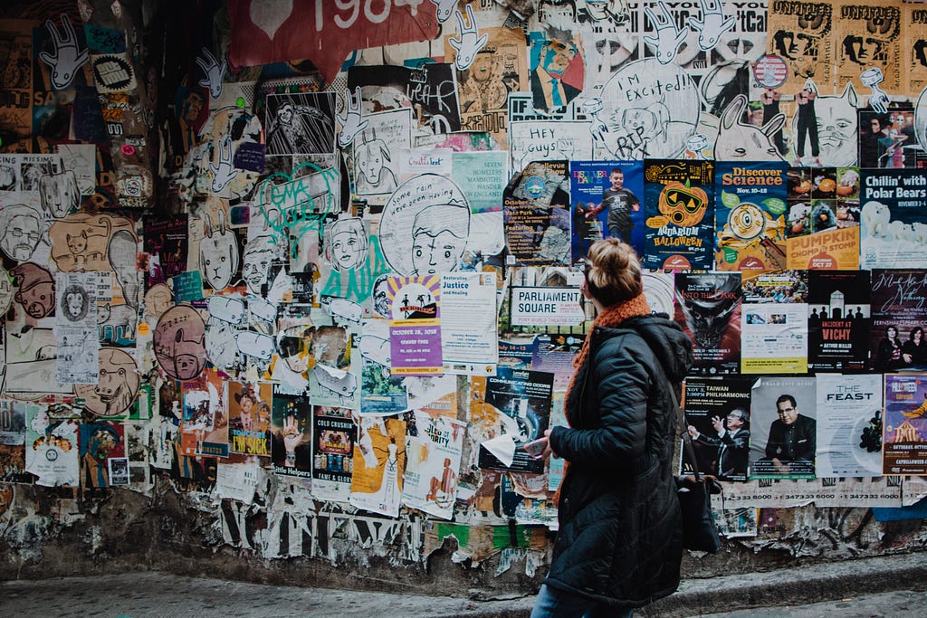 a person standing in front of a wall filled with flyers