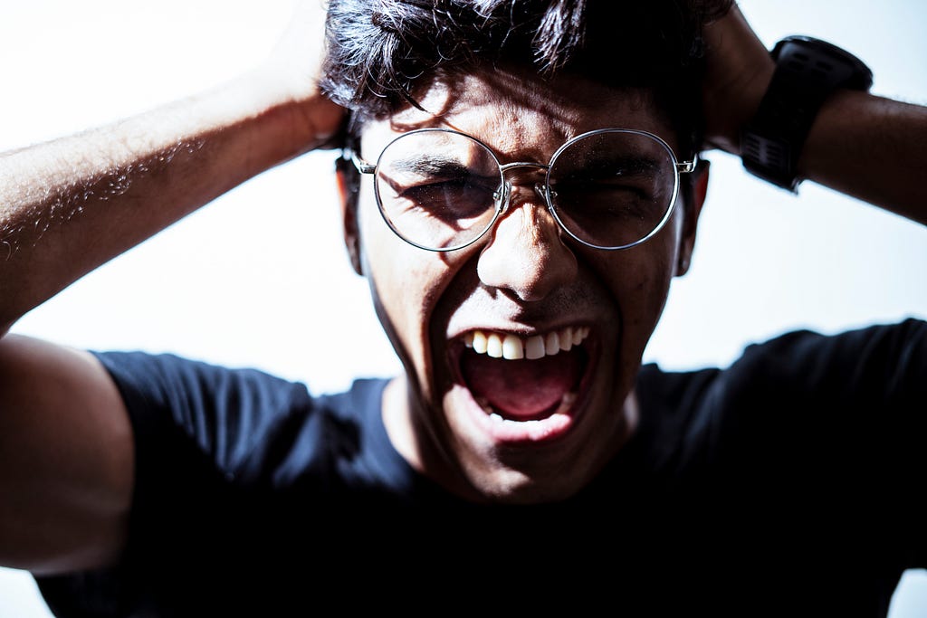 A man with glasses screaming into the camera