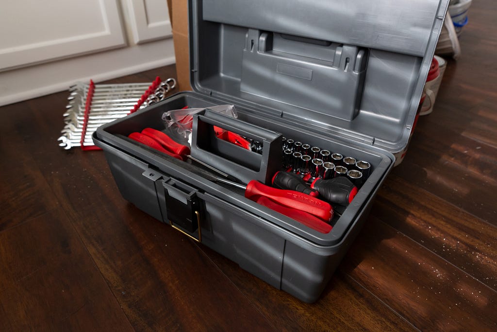 Grey toolbox filled with tools like screwdrivers