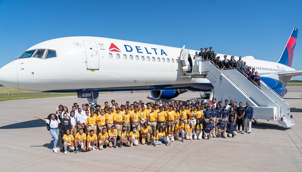 A group shot of OBAP and ACE camp students posing with the air crew in front of the Boeing 757