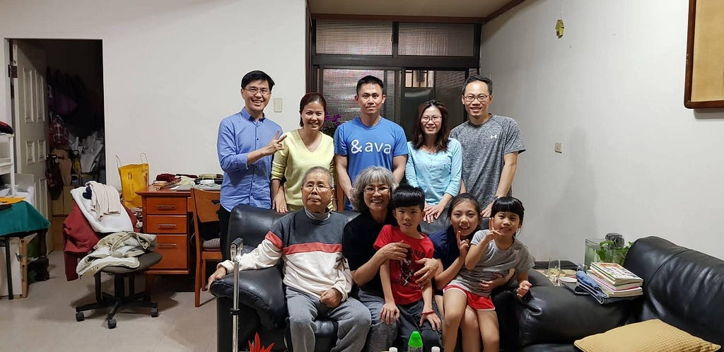 Image Description: Image of Skinner and his 9 family members sitting and standing around a black couch in Taiwan.