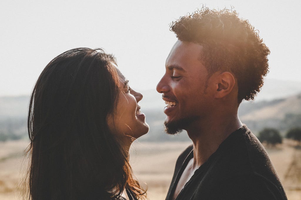 Interracial couple smiling at each other at sunset