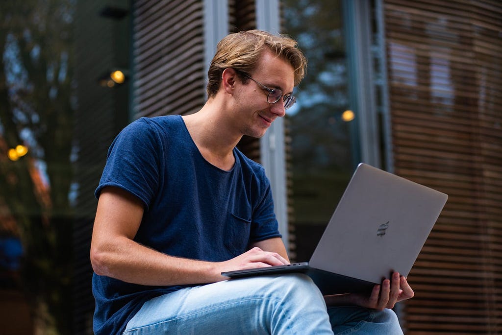 Man smiling while working on his laptop.