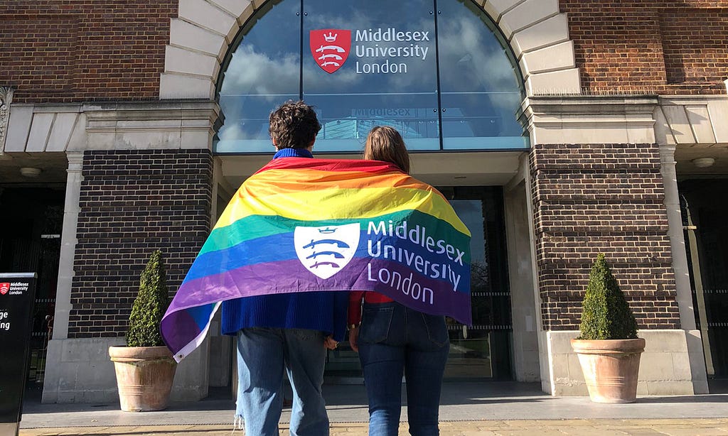 Students with an LGBT+ pride flag outside Middlesex University