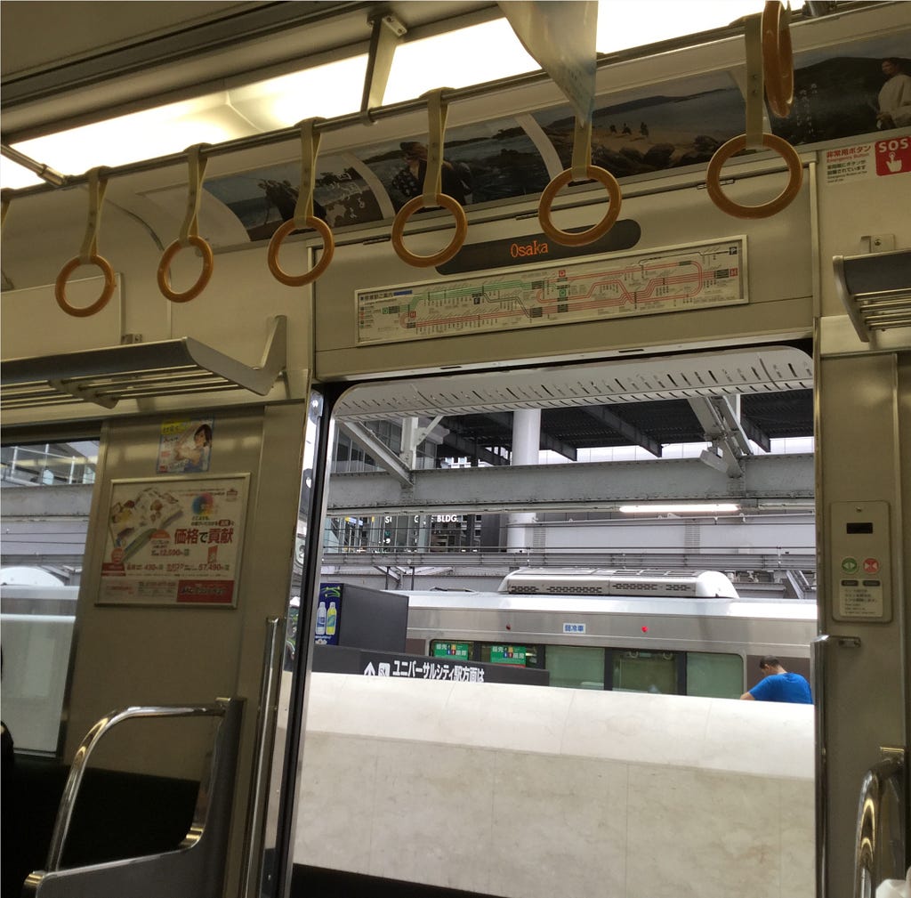 Interior of a Japanese train car with the doors open.