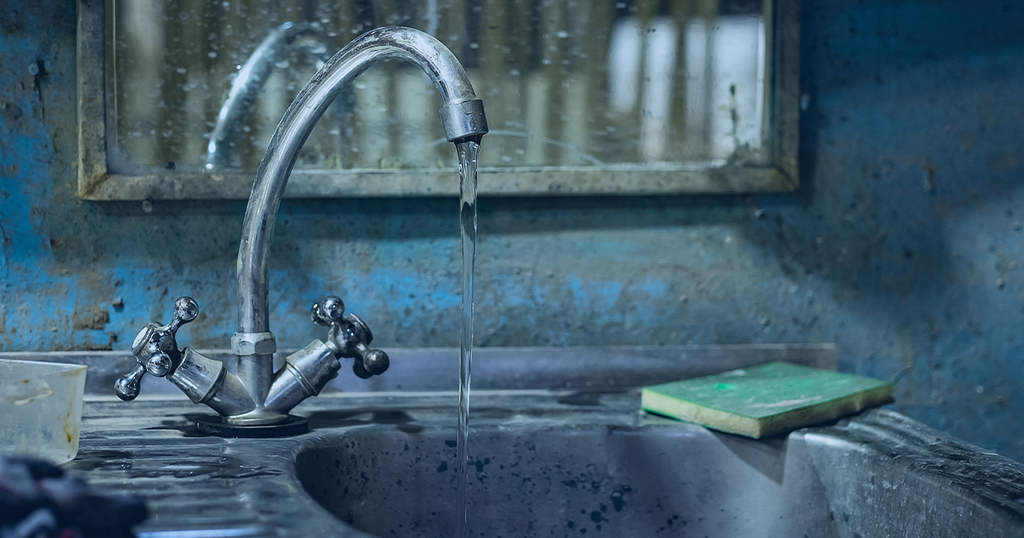 Picture showing water flowing from a tap into a domestic sink in a kitchen