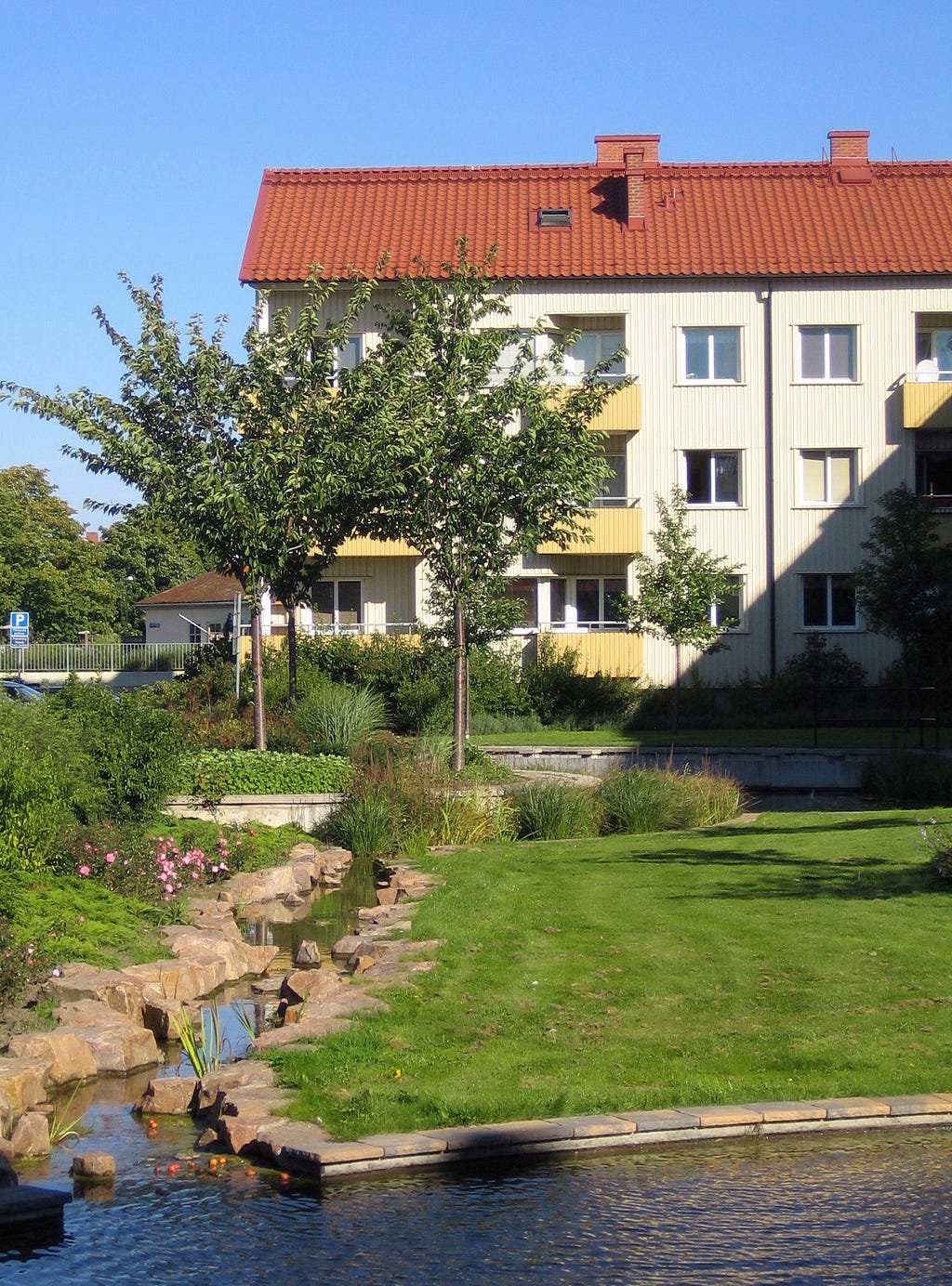 A block of flats surrounded by green and a small river. Urban stormwater management in Augustenborg, Malmö.