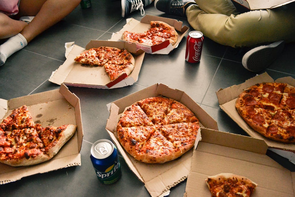 Picture of people sitting around pizza boxes and coke cans