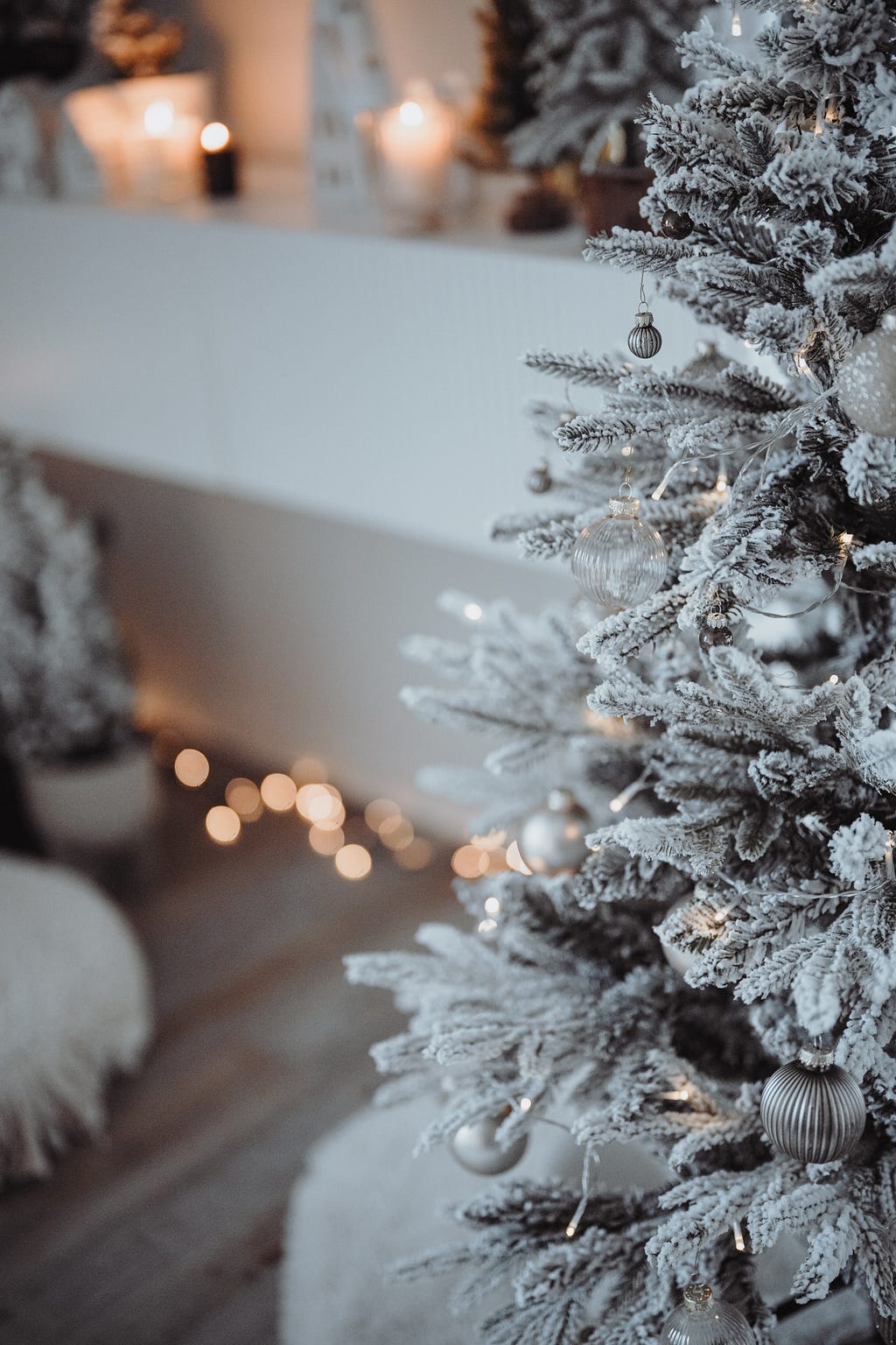 Beautiful white Chrismtas tree with lights and decor around it.