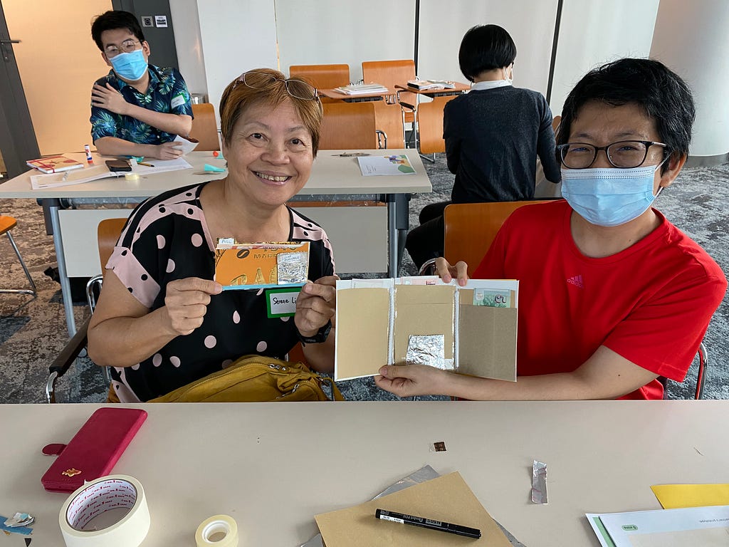 Two women show off the wallets they designed for each other