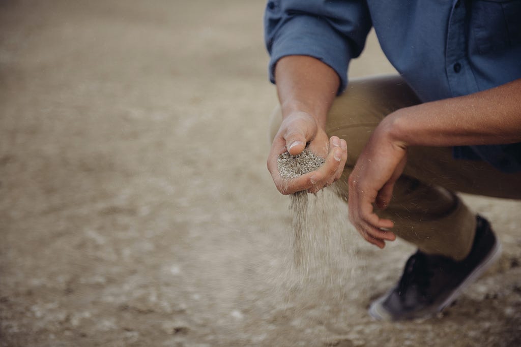 A person sifts through dry soil