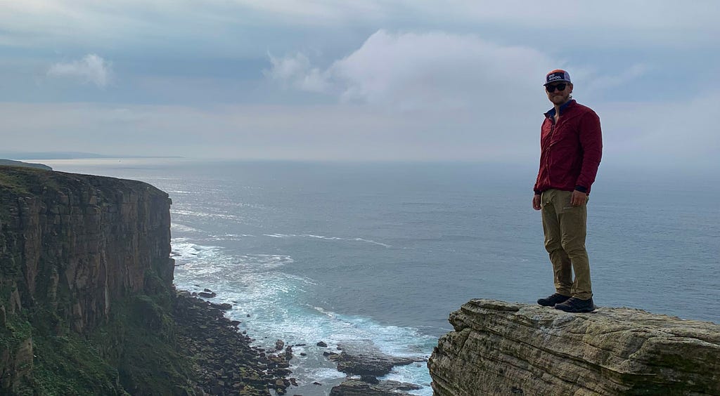 The author on top of a cliff with the ocean on the background.